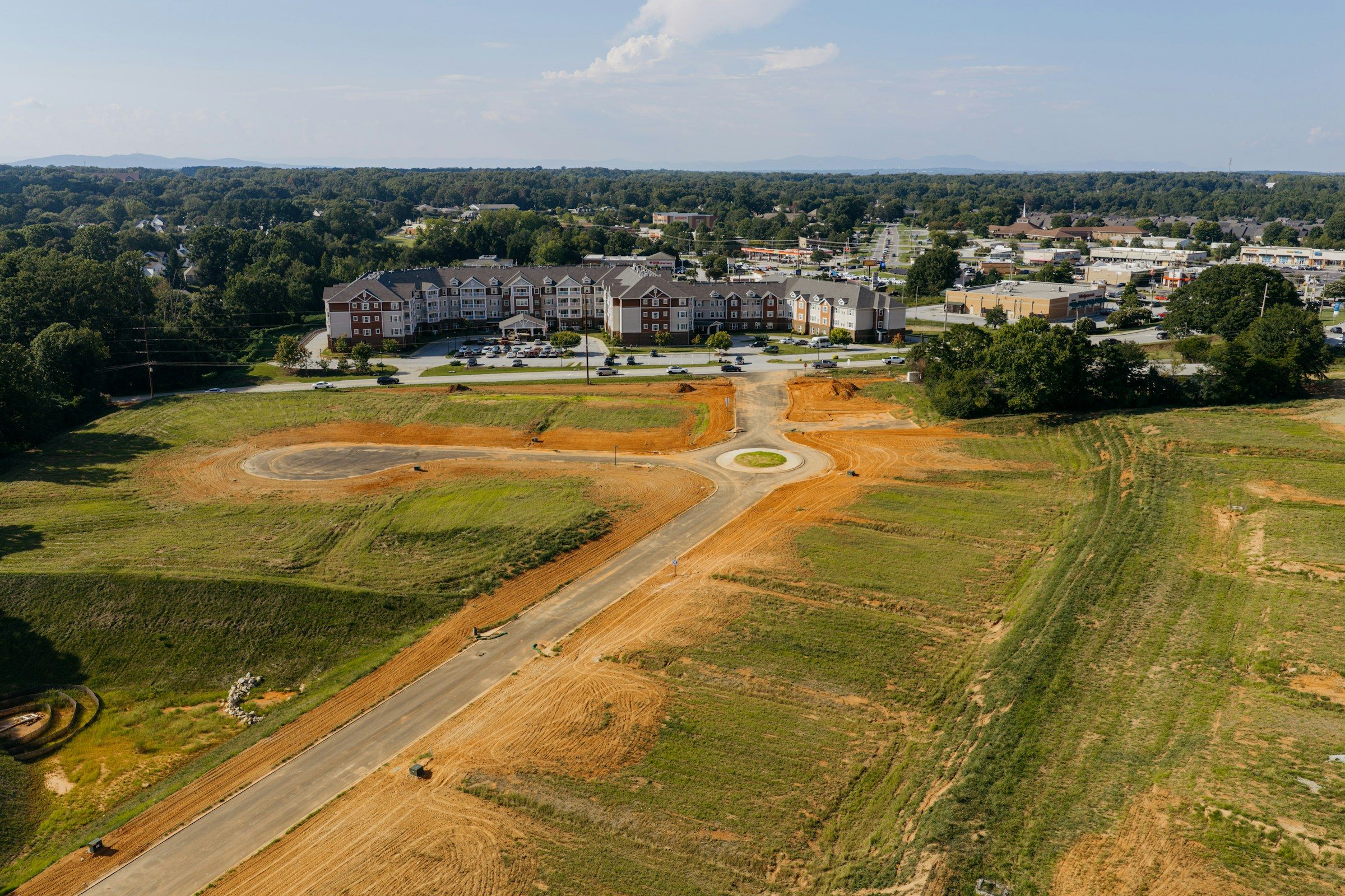 Aerial view of newly graded lots and a new road beside an established neighborhood